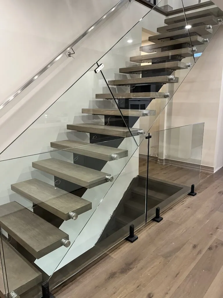 Zig-zag mono stringer floating staircase with spigot and standoff glass railing, featuring a modern geometric open design.