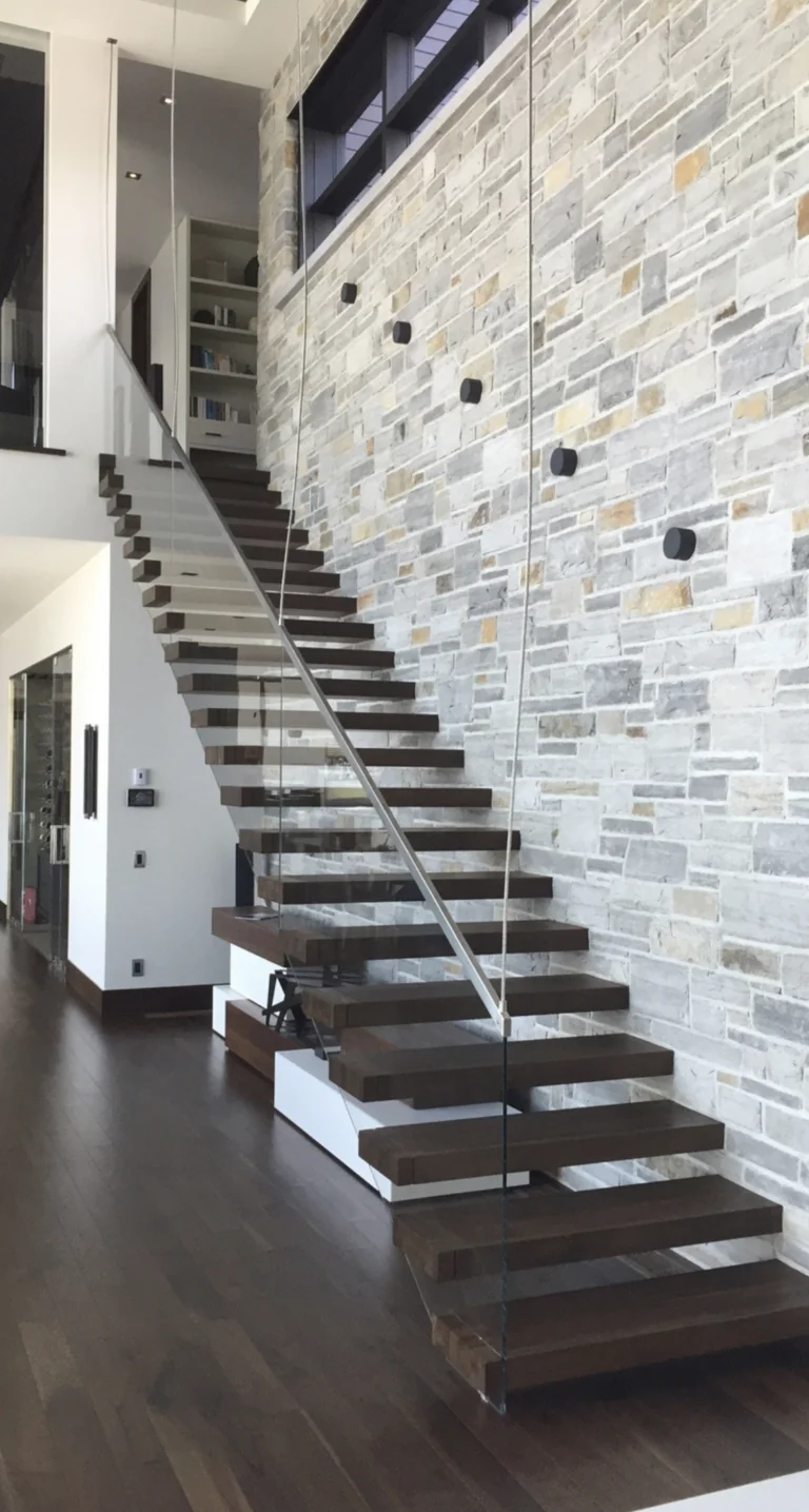 mono-stringer staircase with open treads beside a light stone feature wall