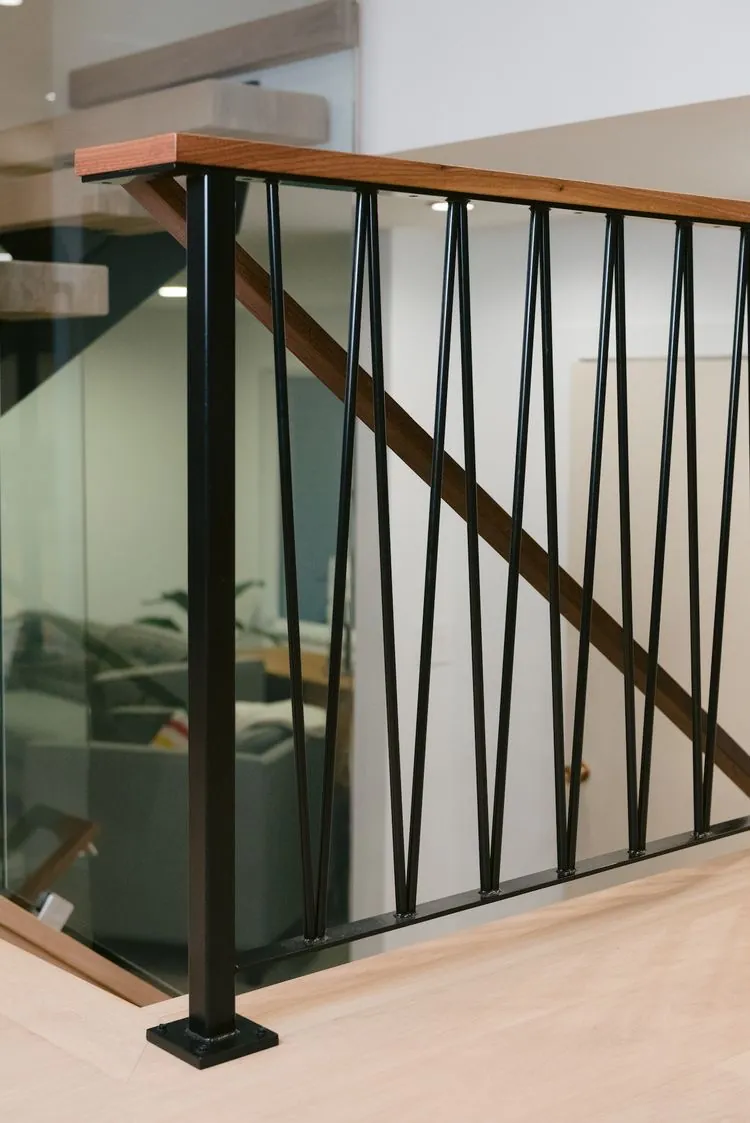Modern indoor railing with geometric zig-zag metal picket design installed along a staircase in a contemporary home.