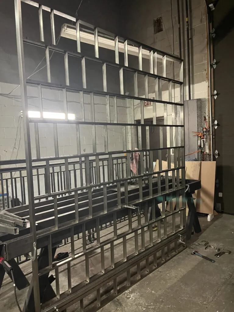 Metal grid room divider frame with a geometric partition design, featuring a modern industrial interior style.