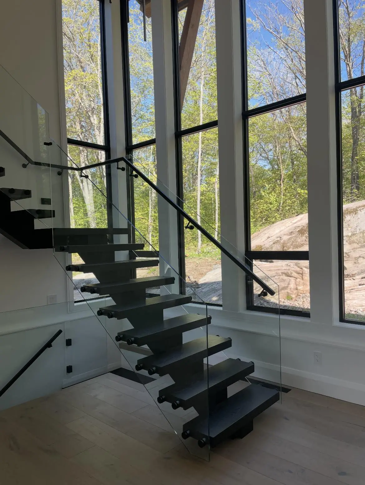 Luxury mono stringer floating staircase with a central steel support and open riser treads in an elegant modern interior.