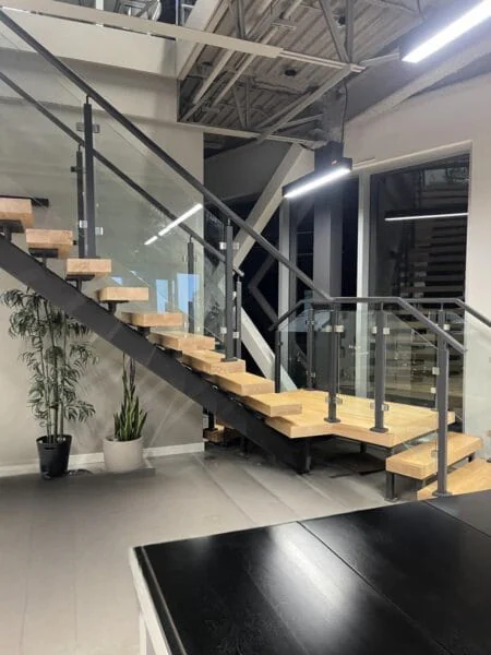 Interior steel staircase with light wood treads and glass railings