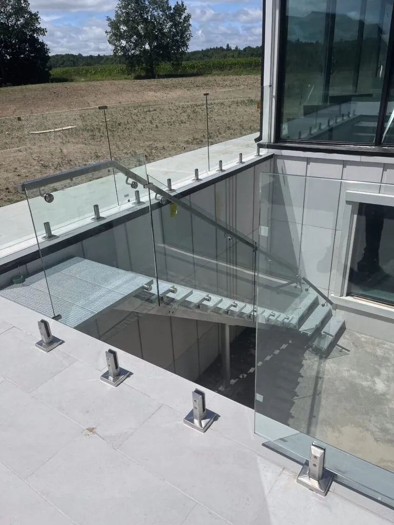 Exterior metal staircase with glass railings around the stairwell opening