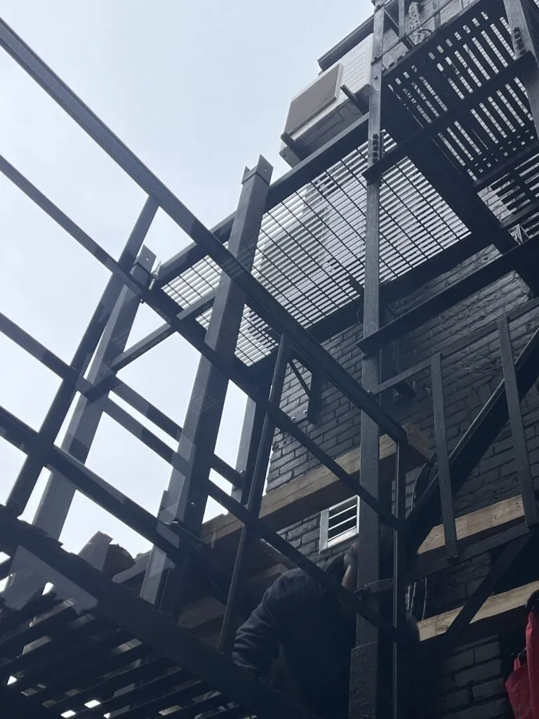 External metal fire escape staircase attached to a building facade for emergency exit access and safety compliance.