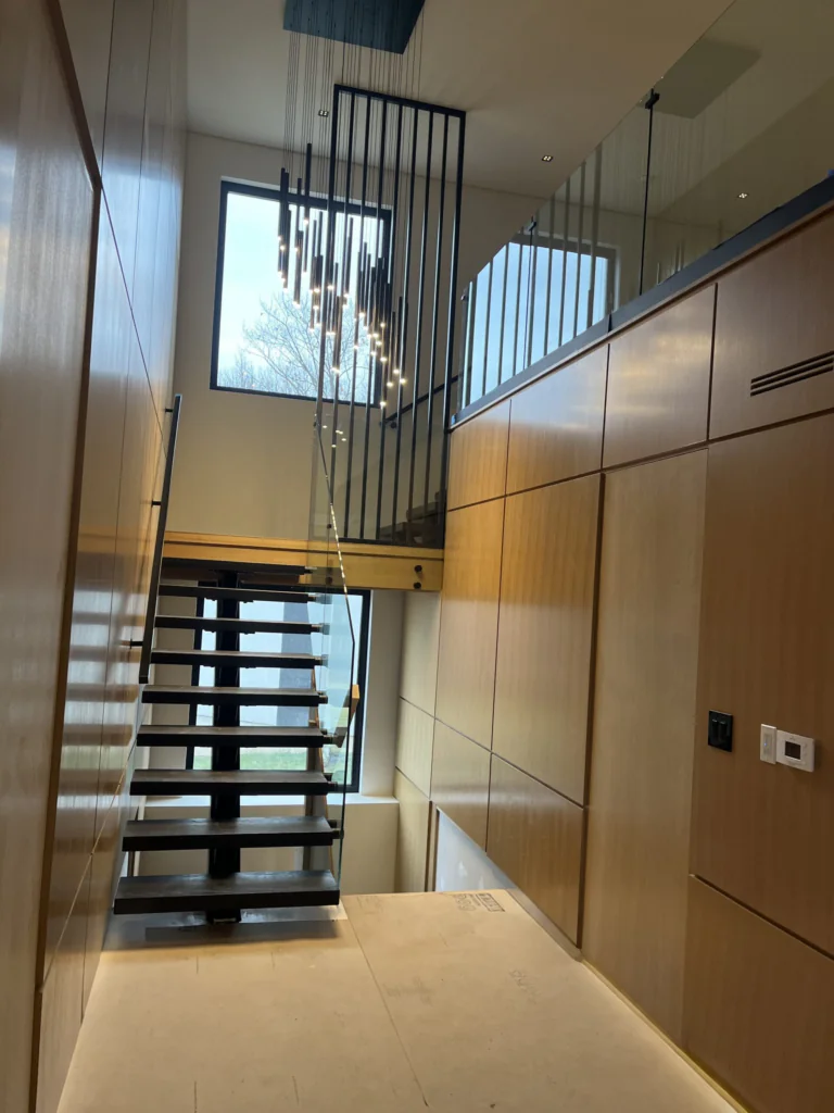 Indoor open-riser staircase in a wood-panelled interior with an upper-level landing.